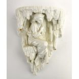 A Royal Worcester blanc de chine wall bracket modelled as a female beauty seated below stalactites,