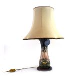 A Moorcroft table lamp of baluster form decorated with woodland trees and flowers at sunset,