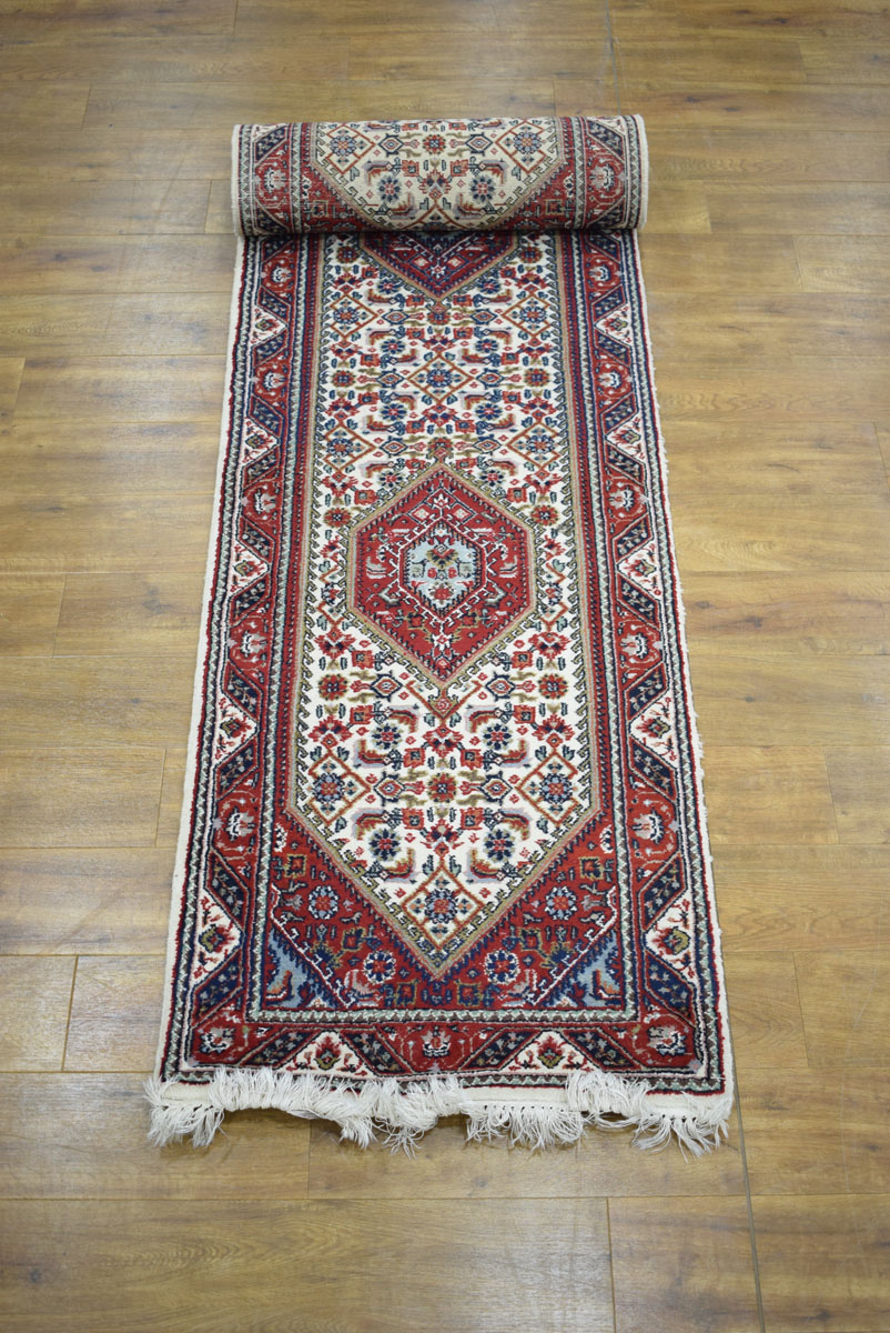 An Iranian carpet runner with a beige and red ground,