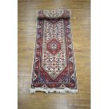 An Iranian carpet runner with a beige and red ground,