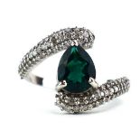 A 14ct white gold crossover ring set pear cut emerald, the shoulders pave set small diamonds,
