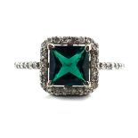 A 14ct white gold ring set square cut emerald within a border of small diamonds,