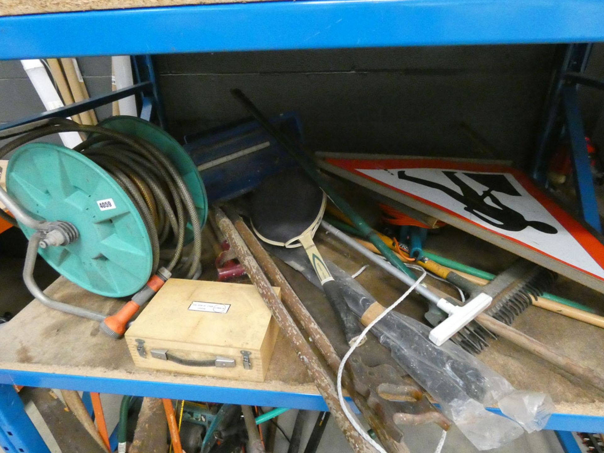 Shelf containing a hose reel and hose, boule set, garden tools, tennis racket, seed spreader and