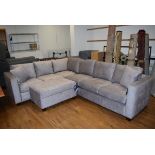 A three section grey faux suede corner sofa including footstool