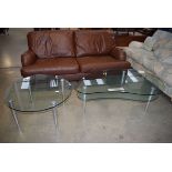 A modern teardrop shaped and 2 tier glass and metal coffee table and a similar round coffee table