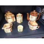 Cage containing novelty cottage teapots, jugs and a sugar bowl