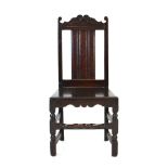 A 17th century oak back stool with a shaped pediment, rectangular back and solid seat,