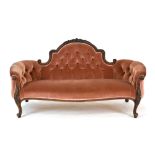 A Victorian mahogany and button upholstered rococo-style sofa on scrolled front legs