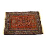 A Caucasian rug with a red ground and repeated geometric motifs,