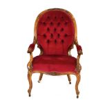 A Victorian walnut and button upholstered high back armchair on scrolled front feet with castors