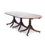 An early 20th century mahogany oval dining table on three columnar pedestals with reeded legs and