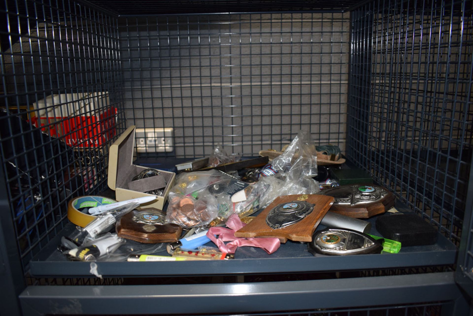 Cage containing wristwatches, loose coinage plus a quantity of badges and medallions