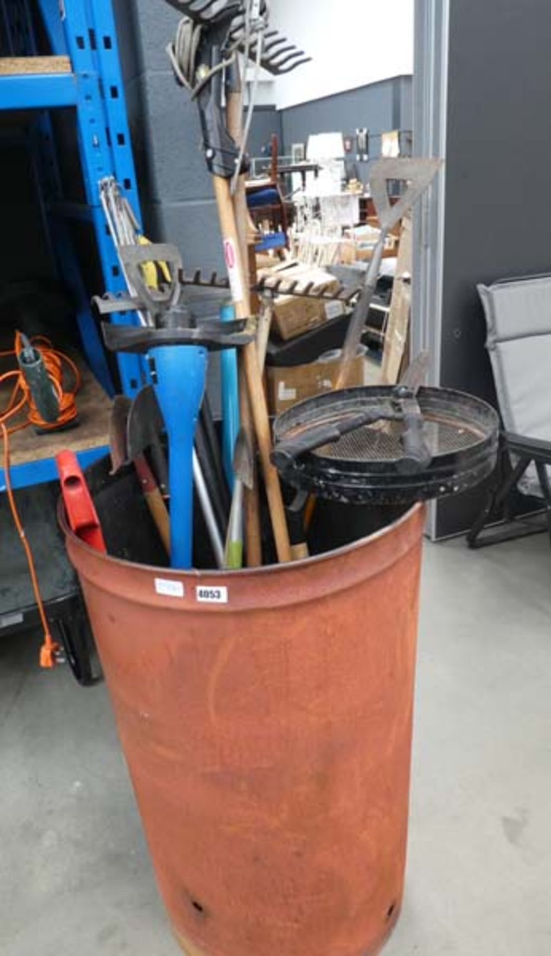 Large metal incinerator with a quantity of garden tools including strimmer, forks, sieves, rakes,