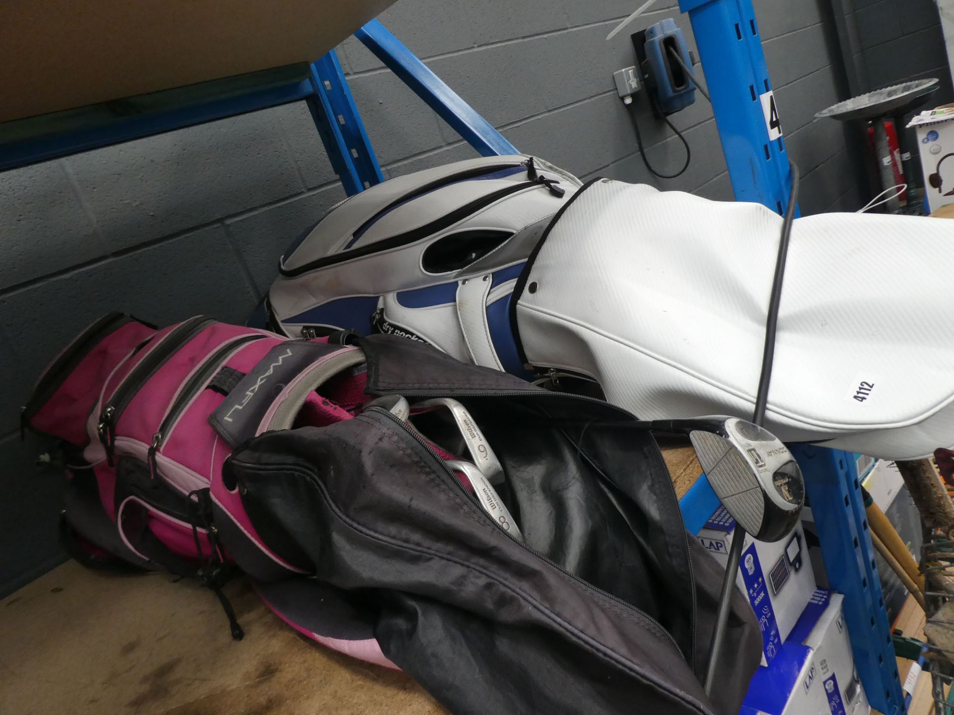 White and blue golf bag and a pink and black golf bag with a set of Wilson clubs