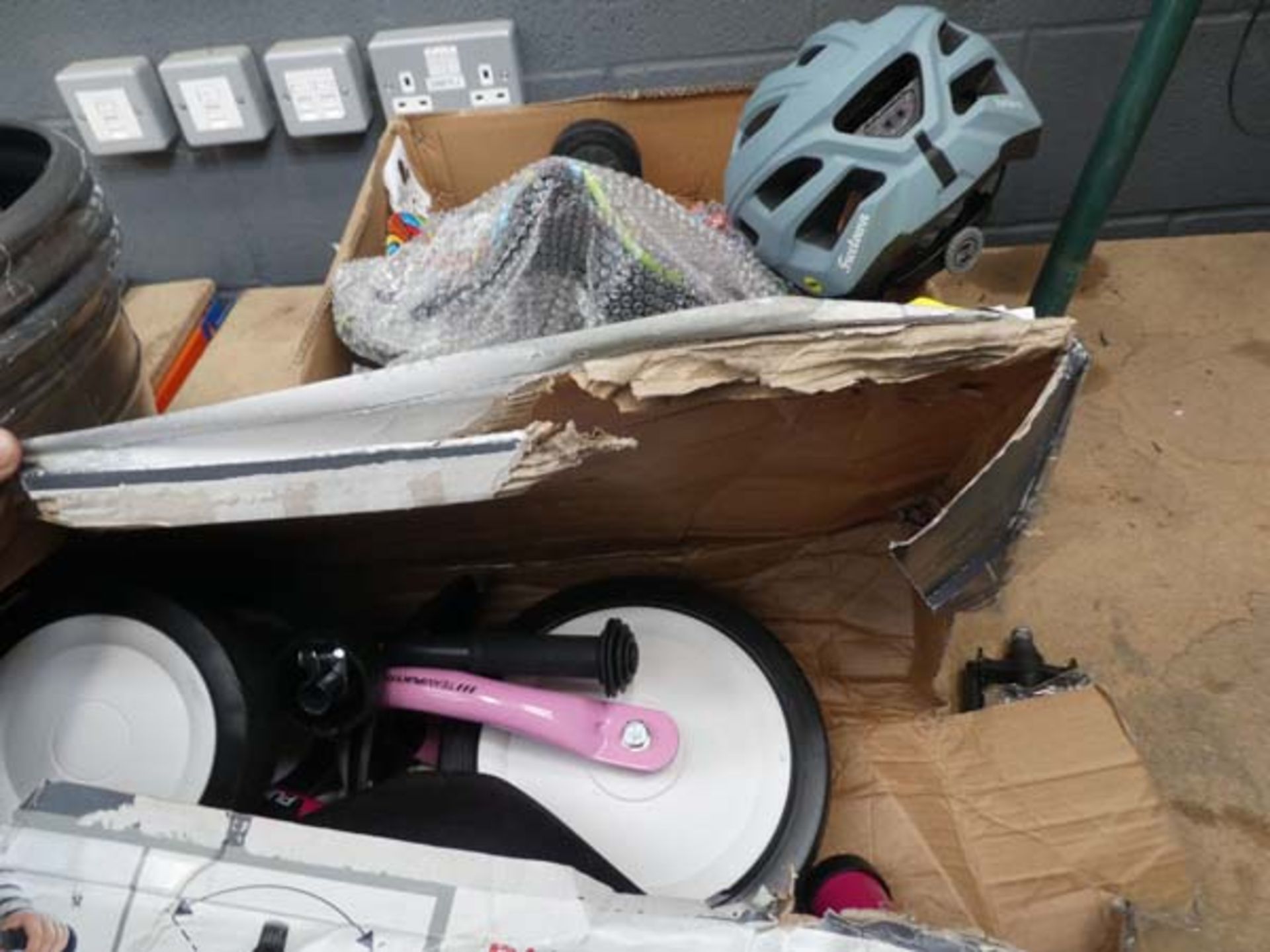 Box containing flatpack trike, helmet, and balance board frame