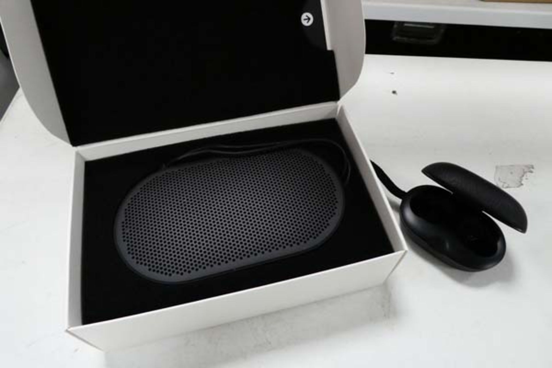 Bang & Olufsen P2 portable bluetooth speaker along with a Bang & Olufsen E8 wireless charging case