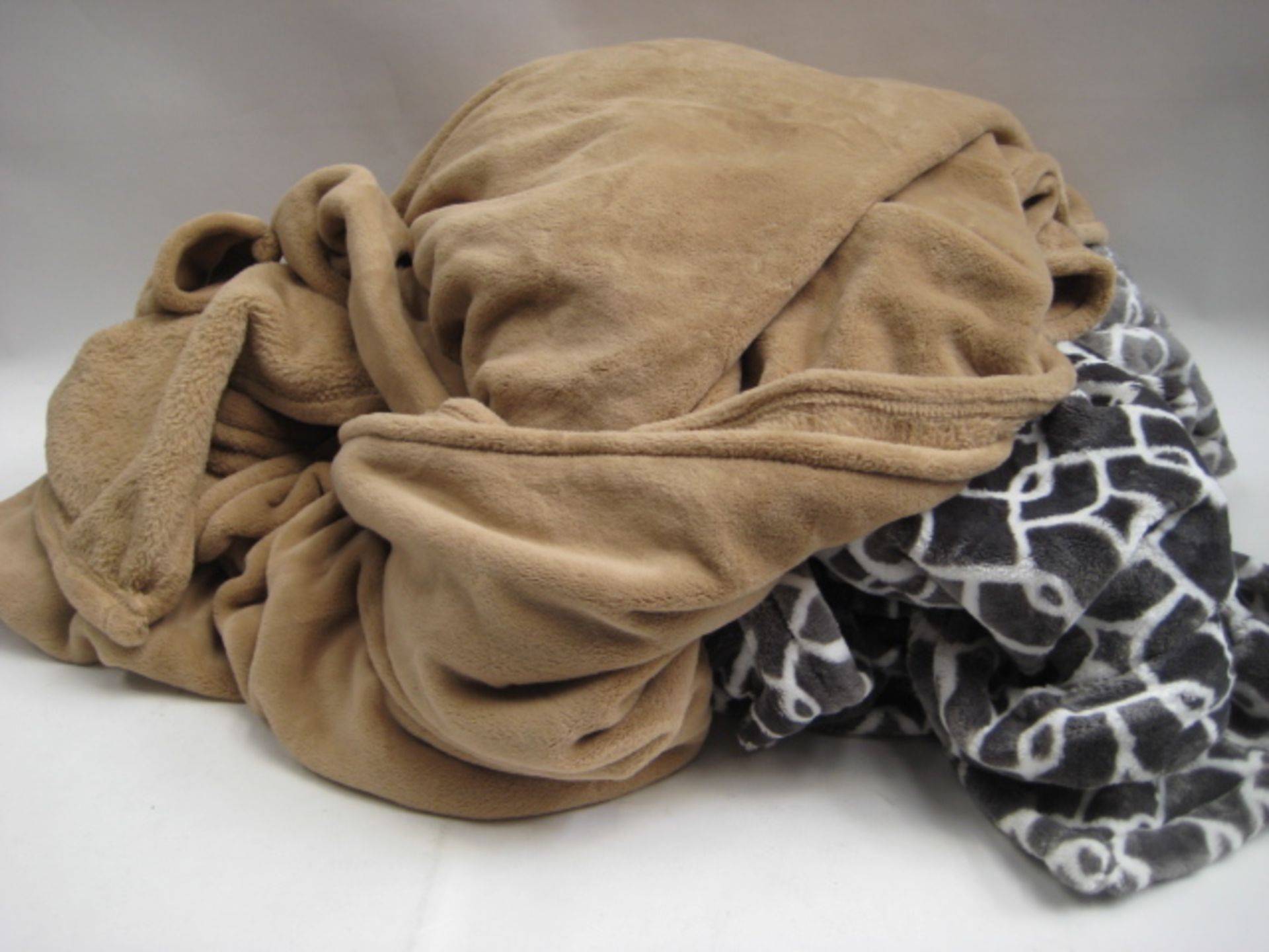 Bag containing 2 throws, 1 in grey with geometric pattern and 1 in camel colour