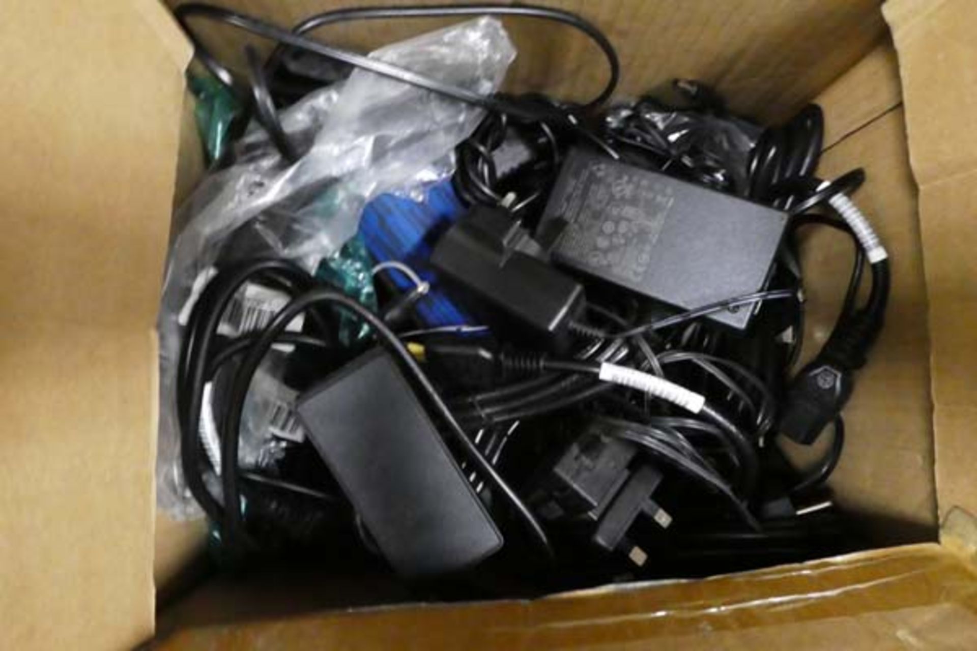Box containing a variety of laptop power supplies and other sundries