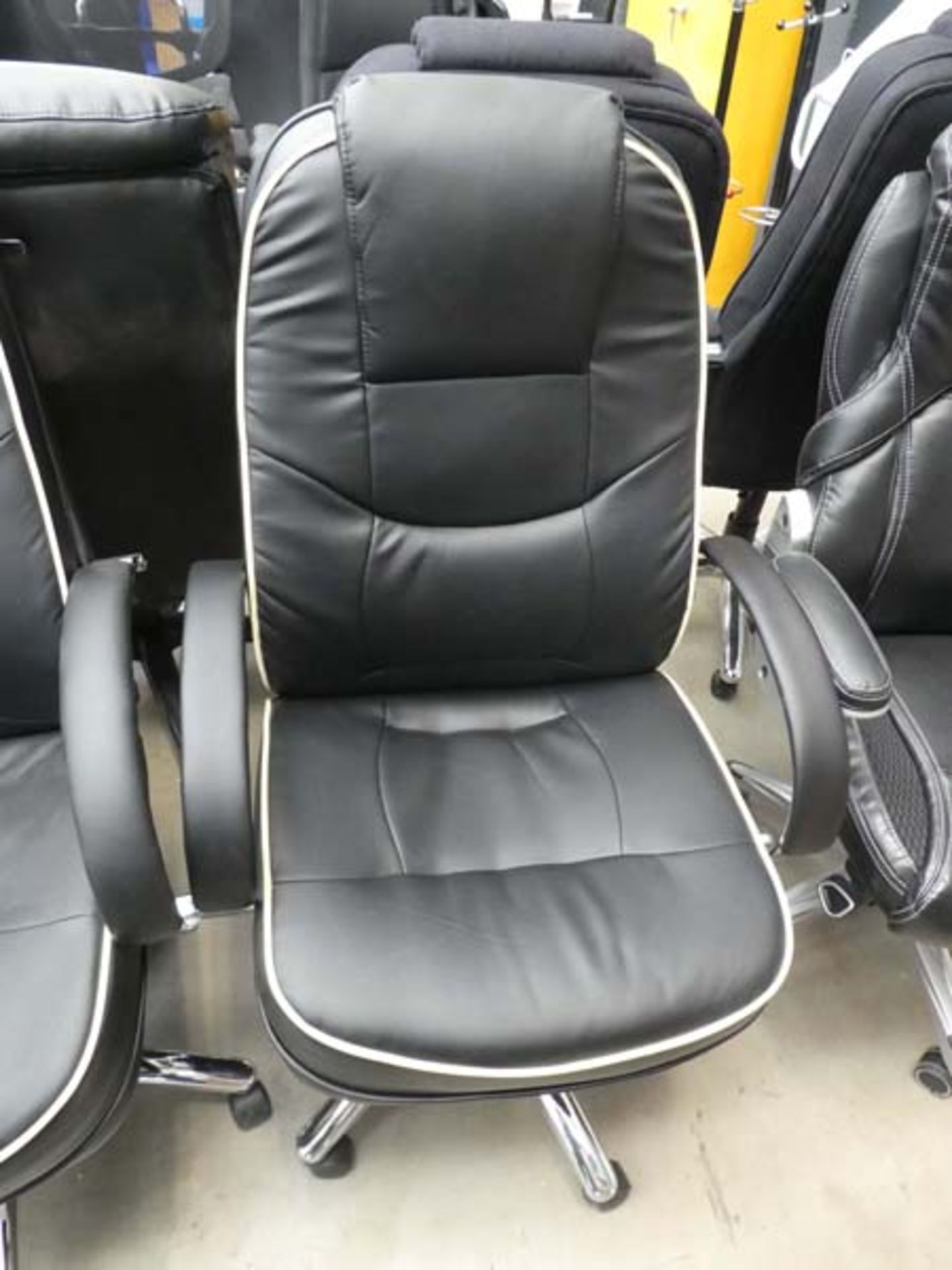 Black high back executive style swivel armchair with cream piping