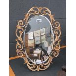 Oval bevelled mirror in decorative gilt and cream frame