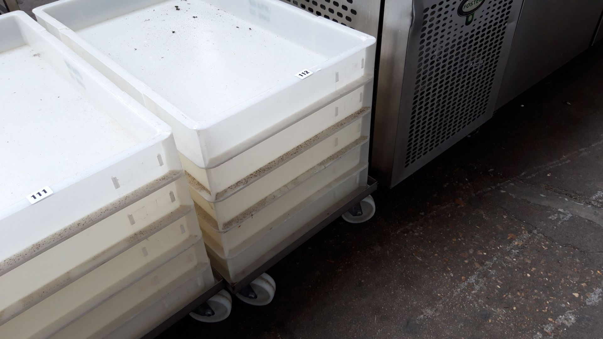 Stack of 5 76cm x 45cm dough trays on a mobile stainless steel trolley