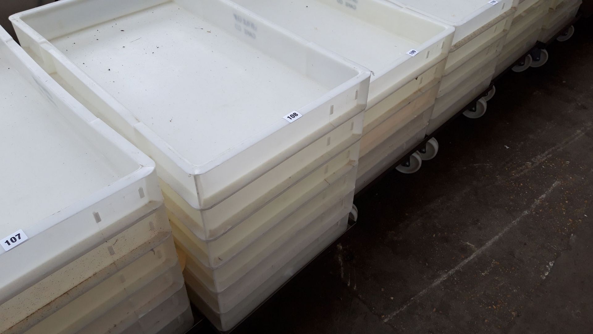 Stack of 6 76cm x 45cm dough trays on a mobile stainless steel trolley