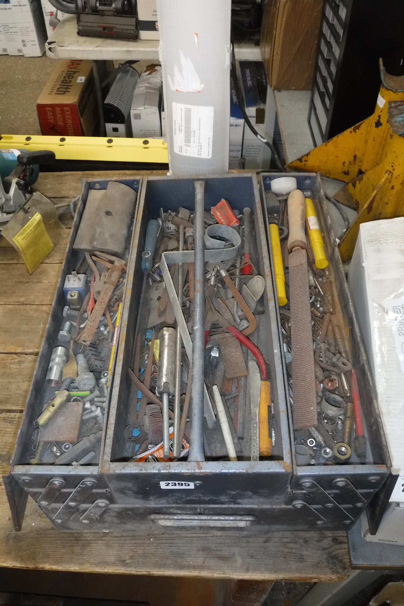 Red metal toolbox containing spanners with cased socket set and mobile wheeled toolbox containing