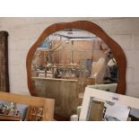 Unframed circular mirror mounted on teak backboard