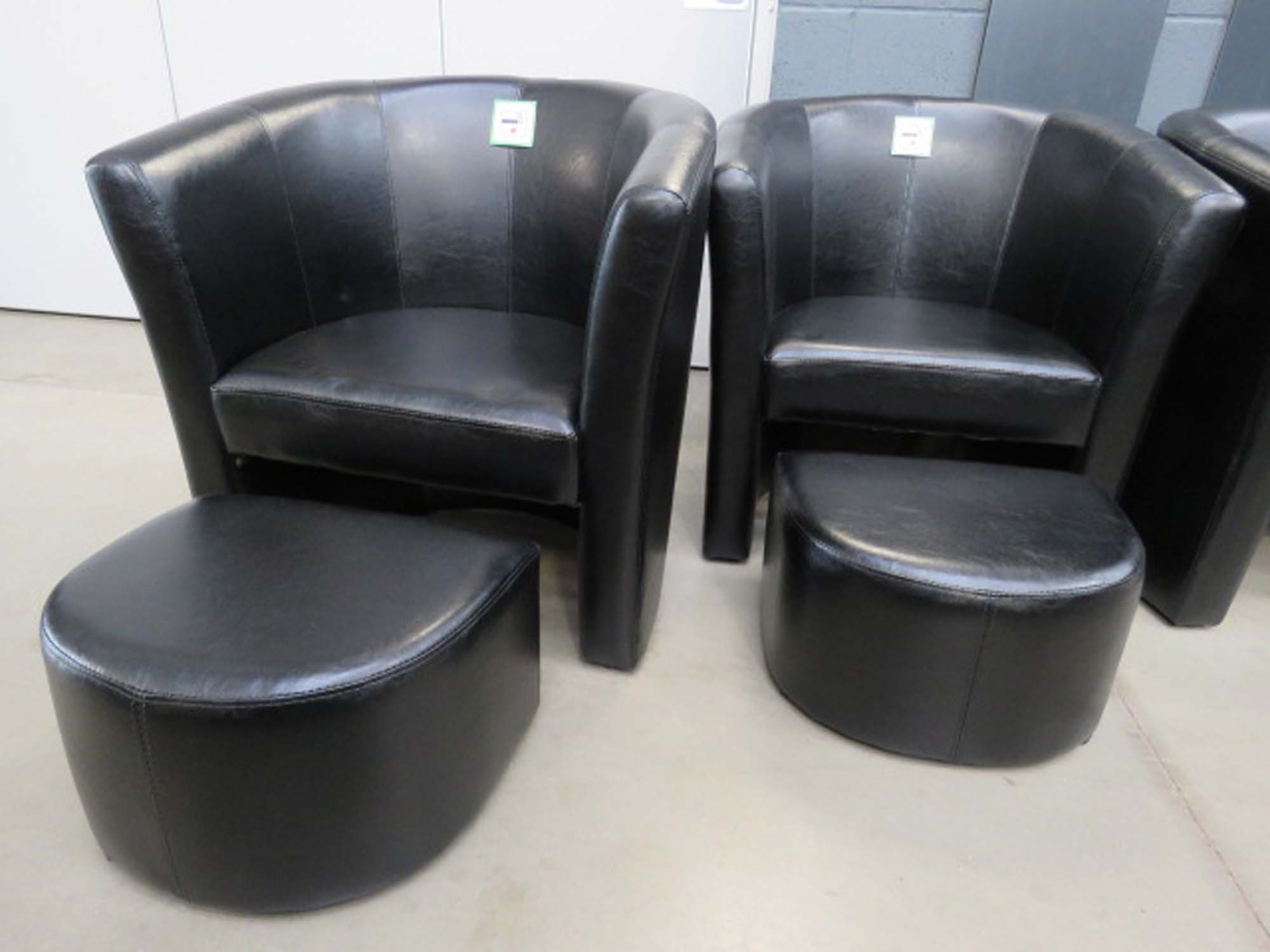 Pair of black leather effect tub chairs with footstools