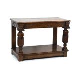 An oak buffet/serving table, the chamfered surface over a carved frieze drawer,