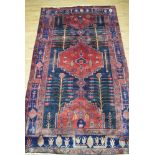 An Iranian hand-woven wool carpet, the red and blue ground with stylised motifs and symbols,