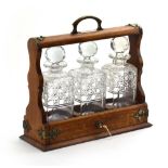 A Victorian oak three-bottle tantalus with silver-plated mounts, h.