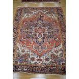 An Indian hand-woven wool carpet, the geometric red and blue ground within matching borders,