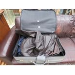 Suitcase with quantity of faux leather and other coats