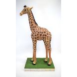 A plastic model of a giraffe on a astro-turf plinth, h.