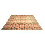 A woollen rug or wall hanging with a pale red geometric ground,