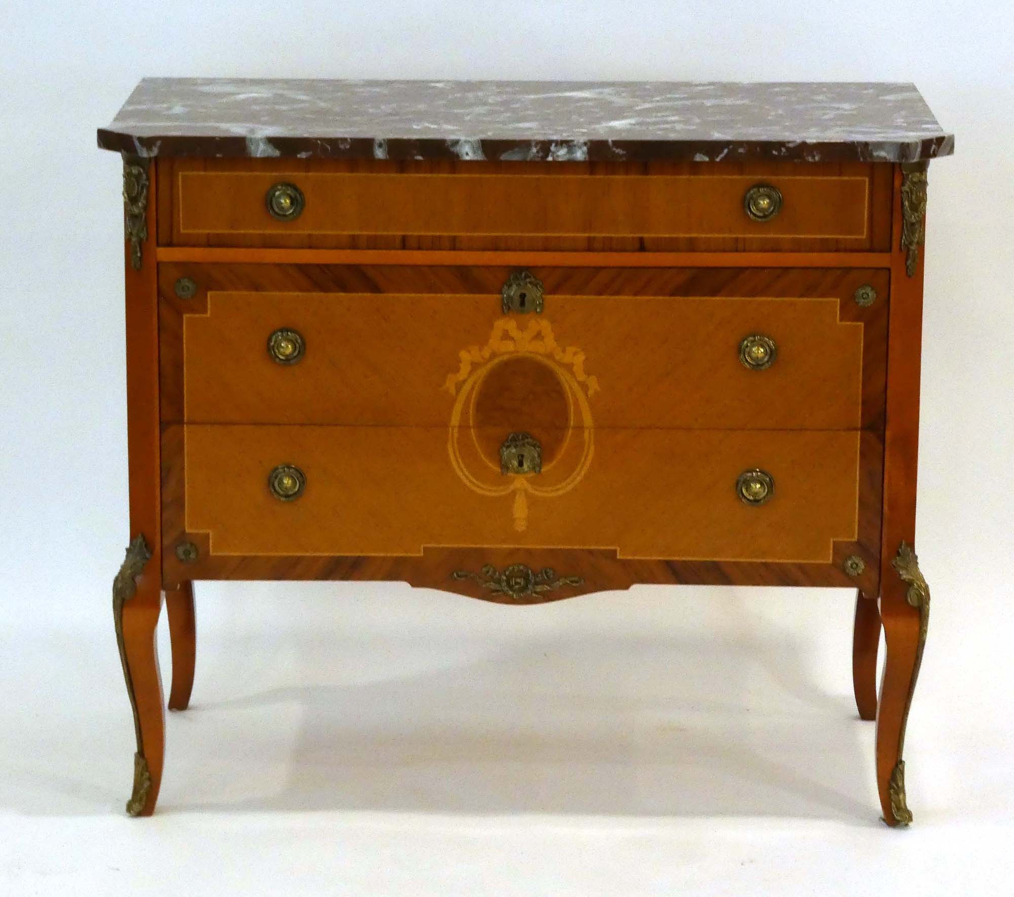 A reproduction commode, the rouge marble surface over three walnut, marquetry and strung drawers,