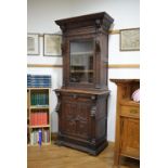 A Victorian carved oak bookcase with one glazed door, one solid door and lion head masks, w.