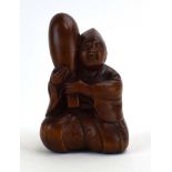 A Japanese boxwood netsuke modelled as a seated courtier practising archery,