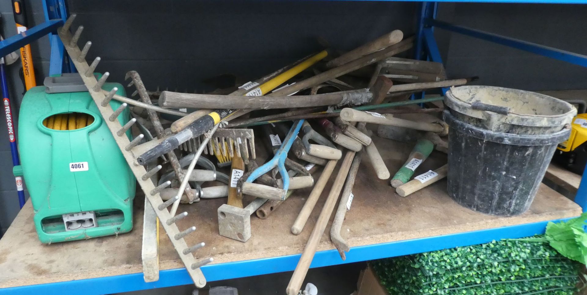 Large bay of assorted tools including hoes, shovels, forks, pickaxes, rakes, hosepipe, hosereel