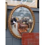 Oval bevelled mirror in decorative gilt frame