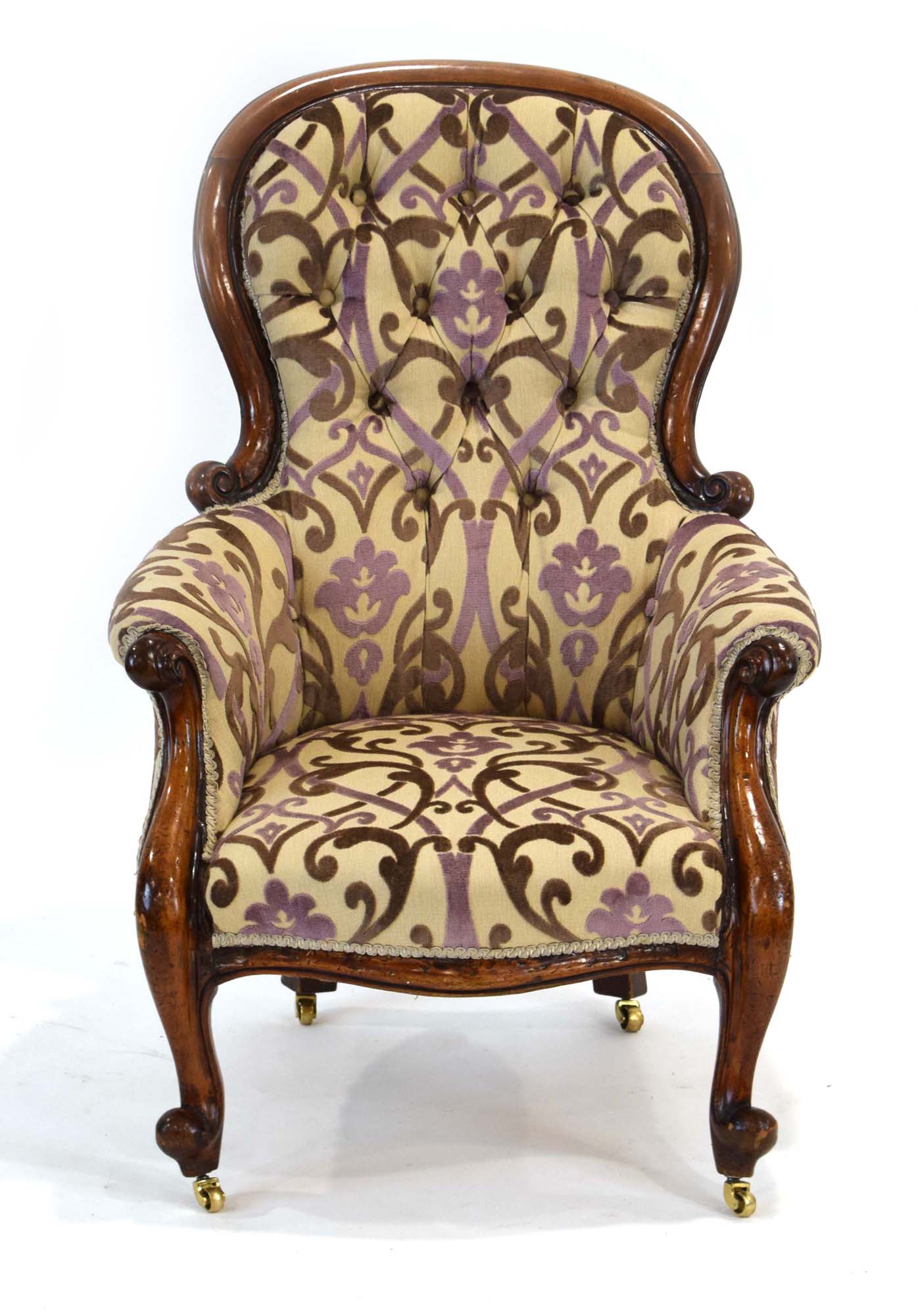 A Victorian mahogany and button upholstered armchair with scrolled front legs on castors