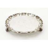 An early 20th century silver card tray of circular form with piecrust border on three scrolled feet,
