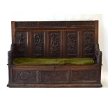 A heavily carved oak settle, the five- panelled back relief decorated with hunting scenes,