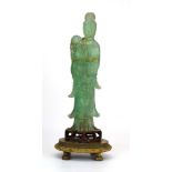 A Chinese green jade-type figure modelled as a standing elder on a wooden and cast metal base,