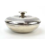 A silver engine turned and Bakelite mounted dressing table container and cover of bun shaped form,