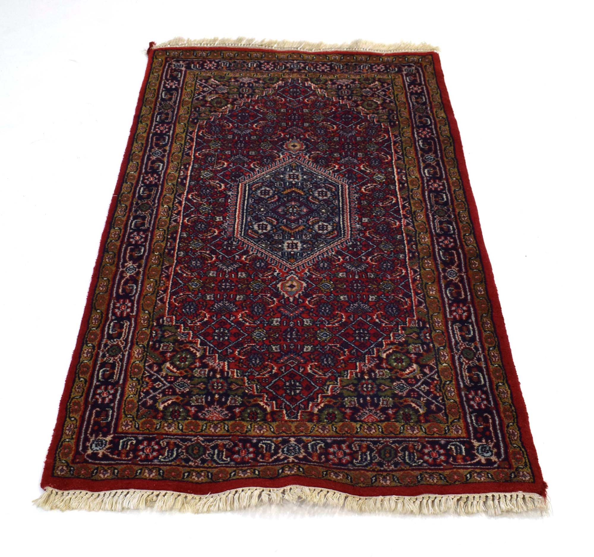 An Indian woolen carpet with a red ground,