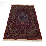 An Indian woolen carpet with a red ground,