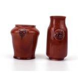 Two miniature Moorcroft vases, each decorated with circular motifs in a plain dark pink glaze,