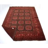 A Pakistani carpet, the red ground with fifteen medallians within matching bands,